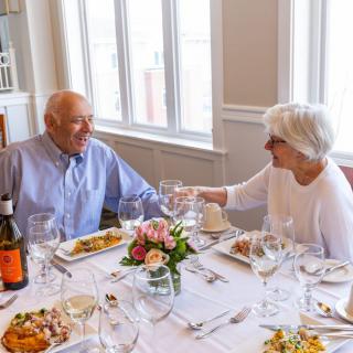 An elderly couple enjoying a meal together at a beautifully set dining table.