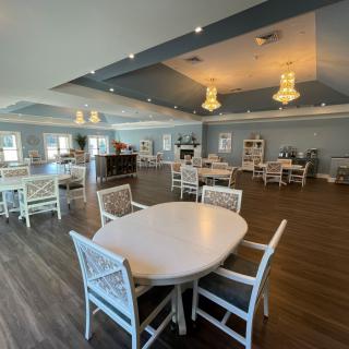 A spacious dining room with elegant chandeliers and neatly arranged tables and chairs.