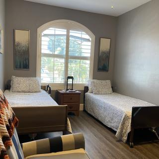 A modern bedroom with twin beds and a large window between them.