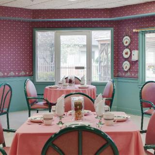 A vintage-themed restaurant dining room with elegantly set tables and pink accents.