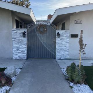 Modern house entrance with a metal gate and stone walls.