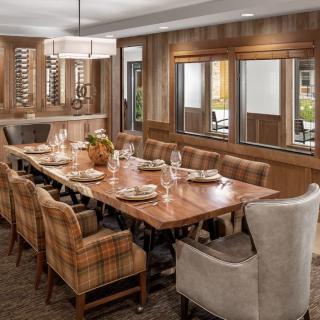 A cozy dining room with a large wooden table and upholstered chairs set for a meal.
