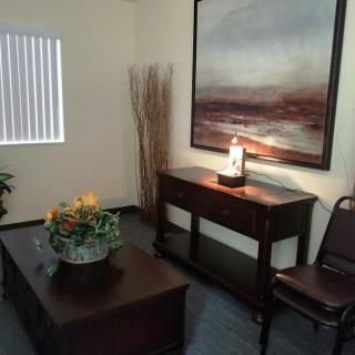 A cozy room with elegant furniture and decor, featuring a painting, lamp, and plant.