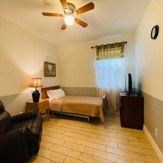 A cozy room featuring a single bed, a comfortable armchair, and warm lighting.