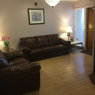 A cozy living room with brown leather couches, a lamp, and a small coffee table adorned with flowers.