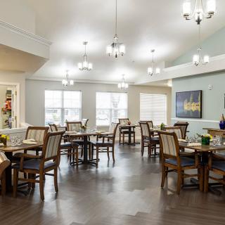 A spacious dining room with elegant lighting and neatly arranged tables and chairs.