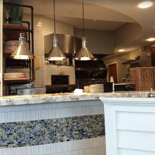 A view of a restaurant kitchen interior with a counter and hanging lights.