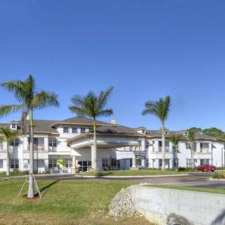 A modern building surrounded by palm trees under a clear blue sky.
