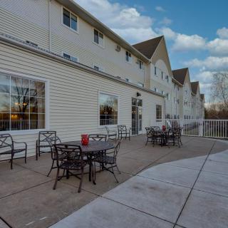 An outdoor patio area with tables and chairs alongside a building under a cloudy sky.