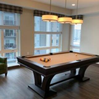 A modern room with a billiards table and large windows.