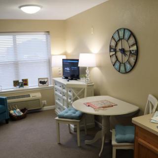 Cozy living room with a small dining table and decorative clock.