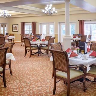 A well-arranged dining room with neatly set tables and elegant chandeliers.