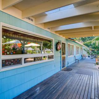 A sunny blue house with a wooden porch and large windows.