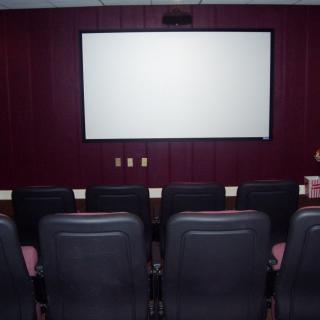 A cozy home theater with comfortable seating facing a large movie screen.