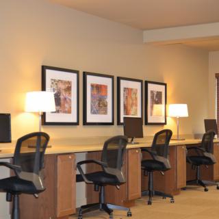 A modern office workspace featuring desks with computers, chairs, and decorative artwork.