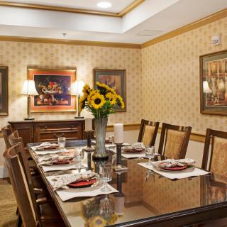 A well-decorated dining room with a table set for guests, featuring sunflowers as the centerpiece.