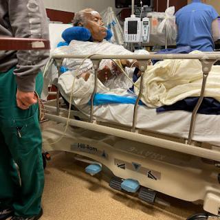 A patient in a hospital bed being attended to by medical staff.
