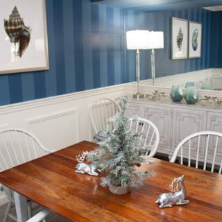 A beautifully decorated dining room featuring a wooden table, white chairs, and elegant holiday accents.