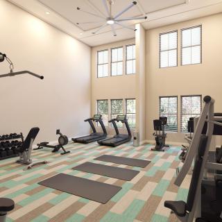 A bright and spacious gym with exercise equipment including treadmills, dumbbells, and workout mats.