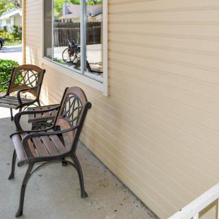 A small porch with two chairs next to a window.