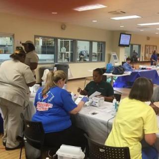 A health fair with medical staff and volunteers assisting attendees.