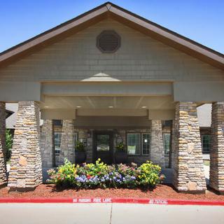 A building entrance featuring stone columns and landscaped greenery.