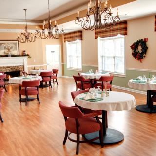 A neatly arranged dining room with elegant chandeliers and wooden flooring.