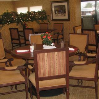 A cozy indoor dining area with a round table and several chairs, decorated with plants.