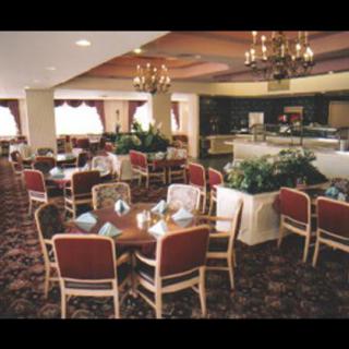 A cozy indoor dining area with tables and chairs arranged in a restaurant setting, featuring chandeliers and a carpeted floor.