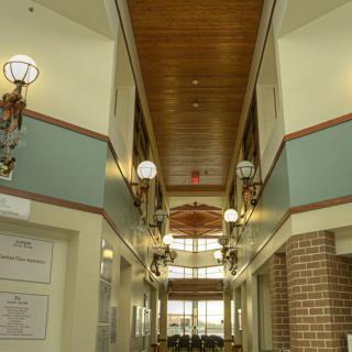 A well-lit hallway with a wooden ceiling and brick accents.