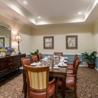 A well-decorated dining room with a long table, surrounded by chairs and adorned with elegant decor.