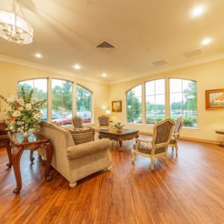 A cozy and elegantly designed living room with ample natural light, featuring comfortable seating and wooden flooring.
