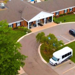Aerial view of a building with a driveway, parking lot, and a white van parked in front.