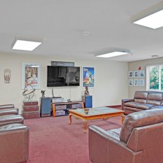 A cozy living room featuring leather sofas, a large television, and various posters on the walls.