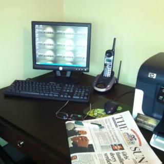 A tidy office desk with a computer, telephone, and newspaper.
