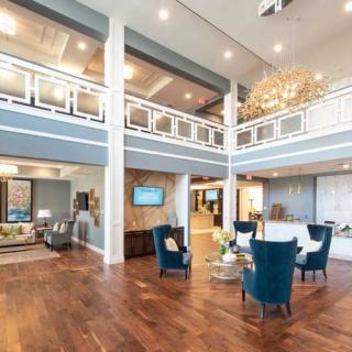 A modern lobby with elegant seating, a large chandelier, and hardwood flooring.