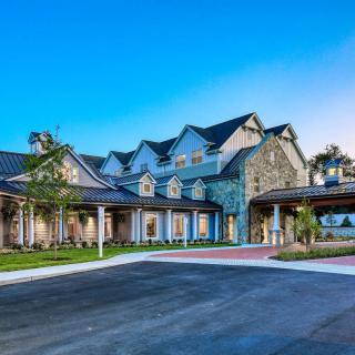 A large residential building with a stone exterior and surrounding greenery.