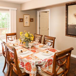 A cozy dining room with a floral tablecloth and sunflower centerpiece.