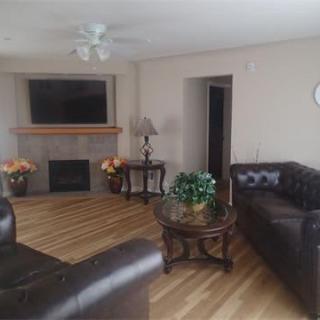 A cozy living room with leather sofas, a fireplace, and a large TV on the wall.