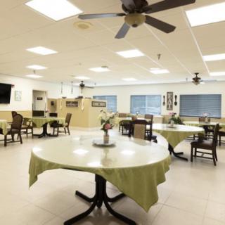 A spacious and well-lit dining room with round tables and ceiling fans.