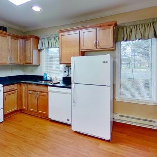 A spacious kitchen featuring wooden cabinets, a white refrigerator, and a large window.