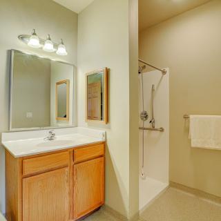 A clean and modern bathroom featuring a sink with a mirror, wooden cabinets, and a shower area.