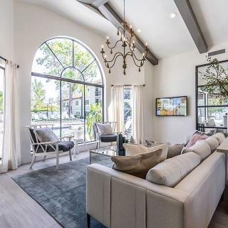 A modern living room with a large arched window and stylish furnishings.