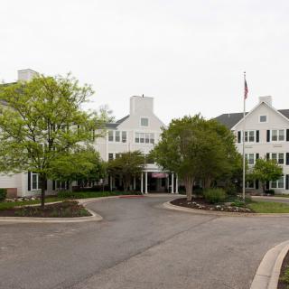 A residential building with a driveway and surrounding trees.
