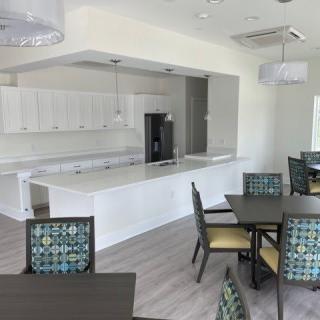 A modern kitchen with white cabinets and an adjoining dining area featuring stylish tables and chairs.