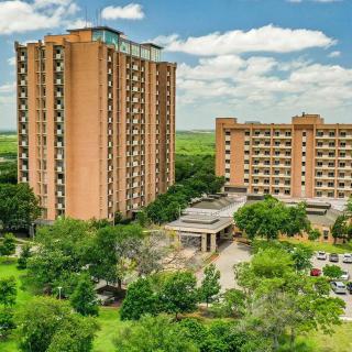 A view of two high-rise residential buildings surrounded by greenery and trees.