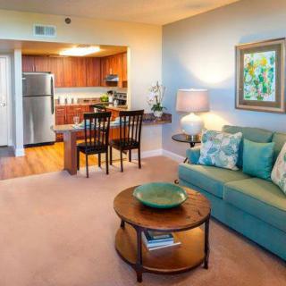 A modern open-concept living area features a cozy sofa, coffee table, and connected kitchen with wooden cabinets.