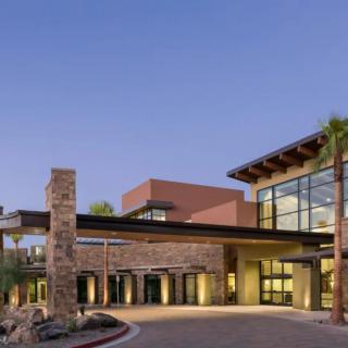 A modern building with large glass windows and a stone exterior at dusk.