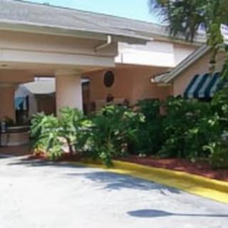 The entrance of a building surrounded by lush greenery and an awning.