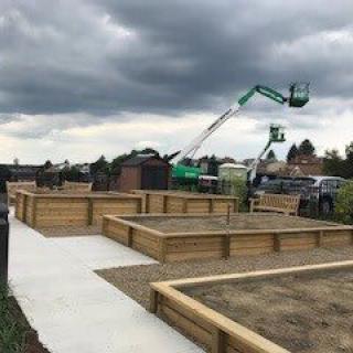 Construction site with wooden raised garden beds under an overcast sky.